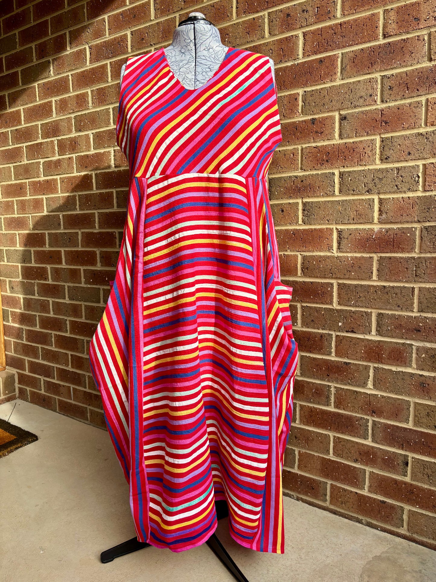 Multicolored striped dress on a mannequin against a brick wall.