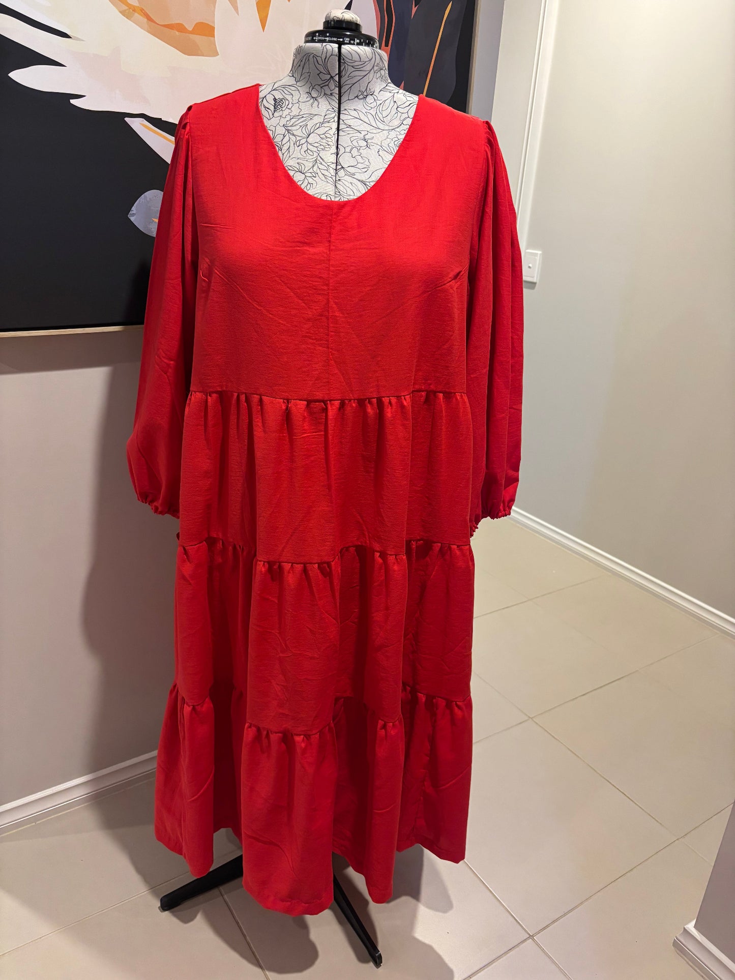 Red dress on a mannequin against a plain wall.