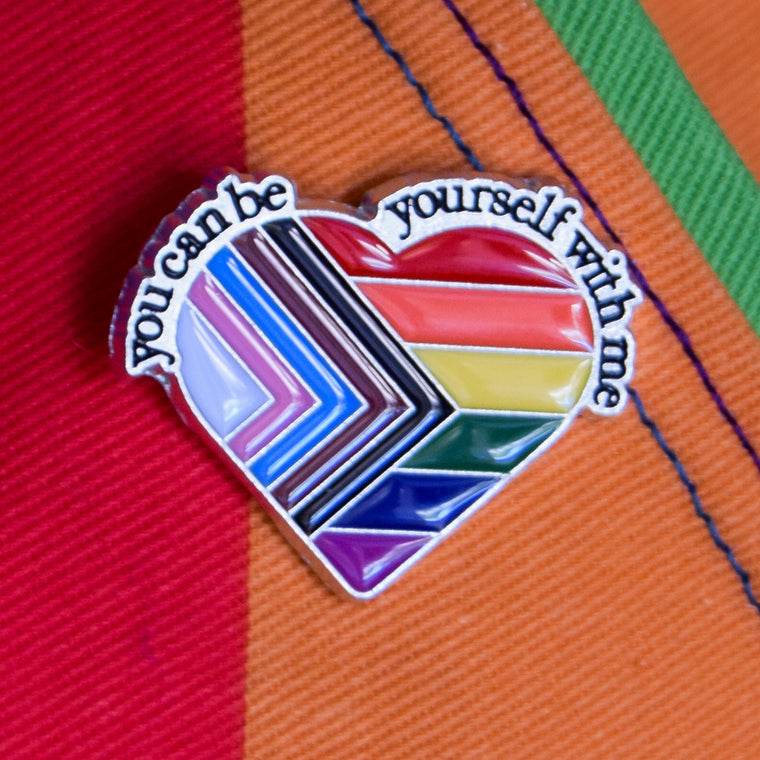 Heart-shaped rainbow pin with text on a rainbow background